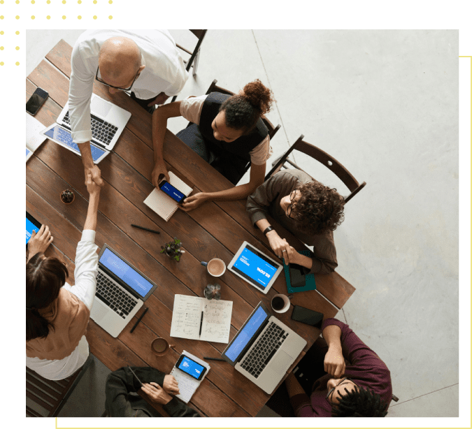 A group of people sitting around a table with laptops.